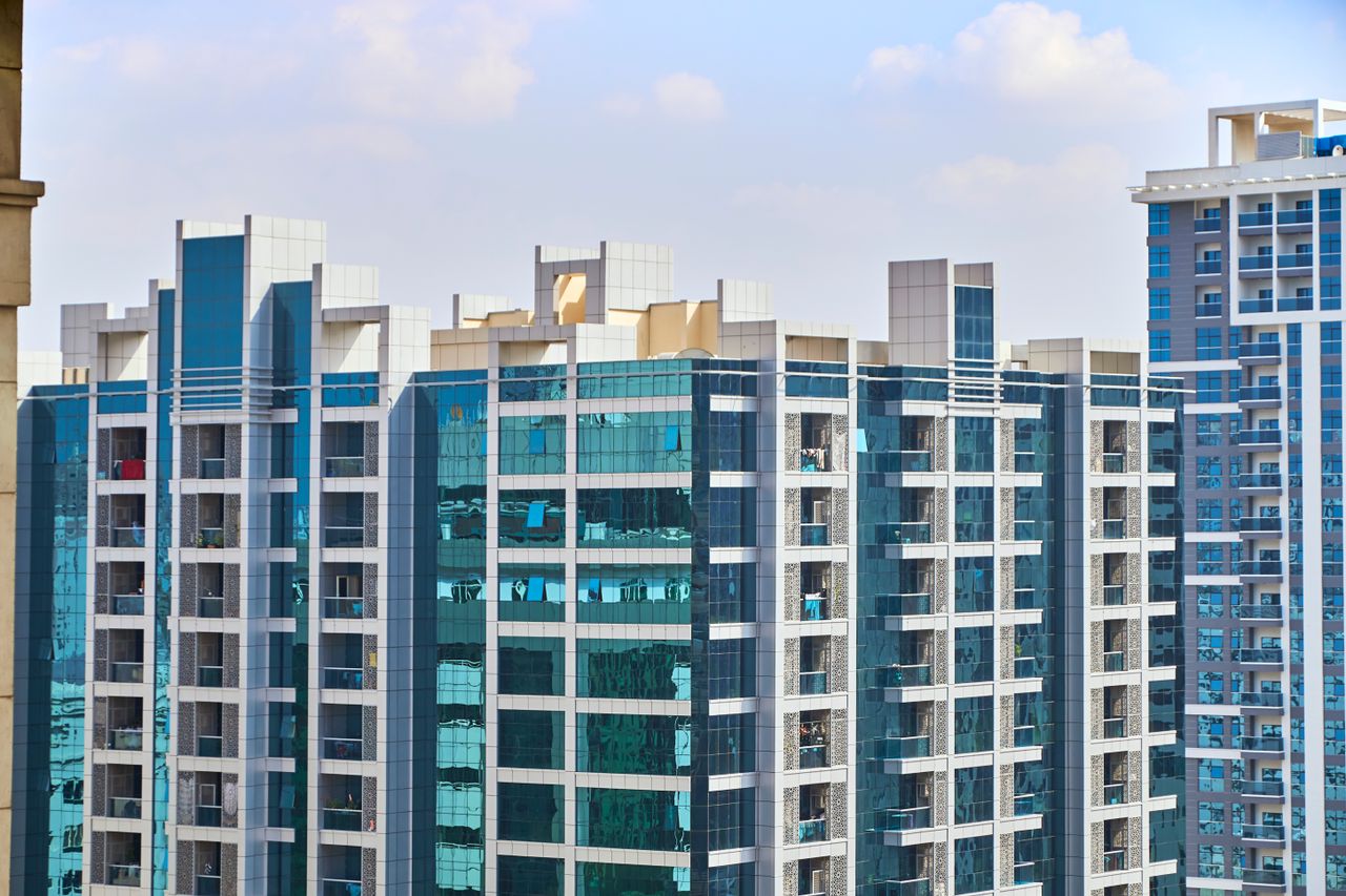 Home A cityscape view of modern high-rise buildings with reflective glass facades under a blue sky.