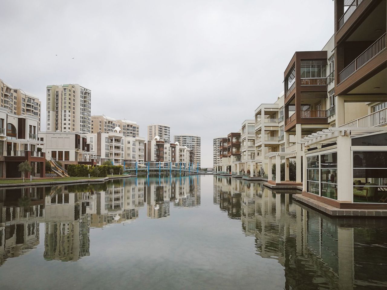 Modern residential buildings reflecting in a tranquil urban canal.