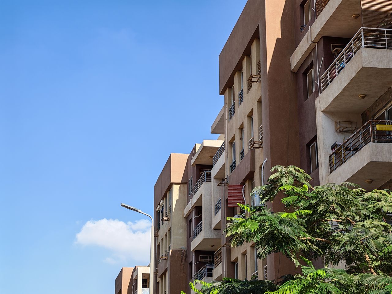 The Art of Drawing Readers In: Your attractive post title goes here Urban apartment building against a bright blue sky with foliage in the foreground.
